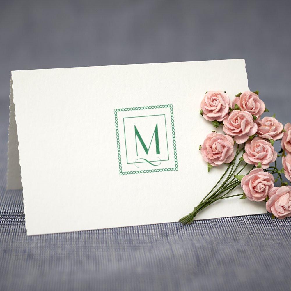 Custom monogram rubber stamp on white card, featuring a decorative green letter M for wedding invitations and stationery.