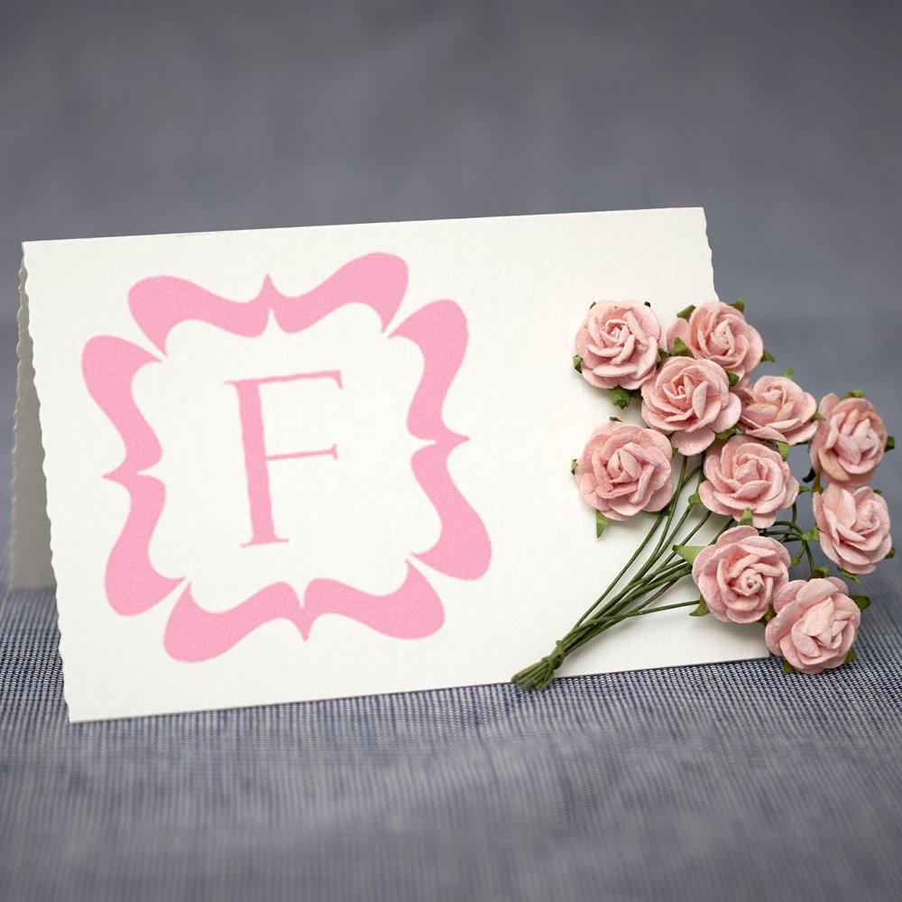 Pink floral monogram rubber stamp with letter F on greeting card, styled with small pink roses for custom stationery.
