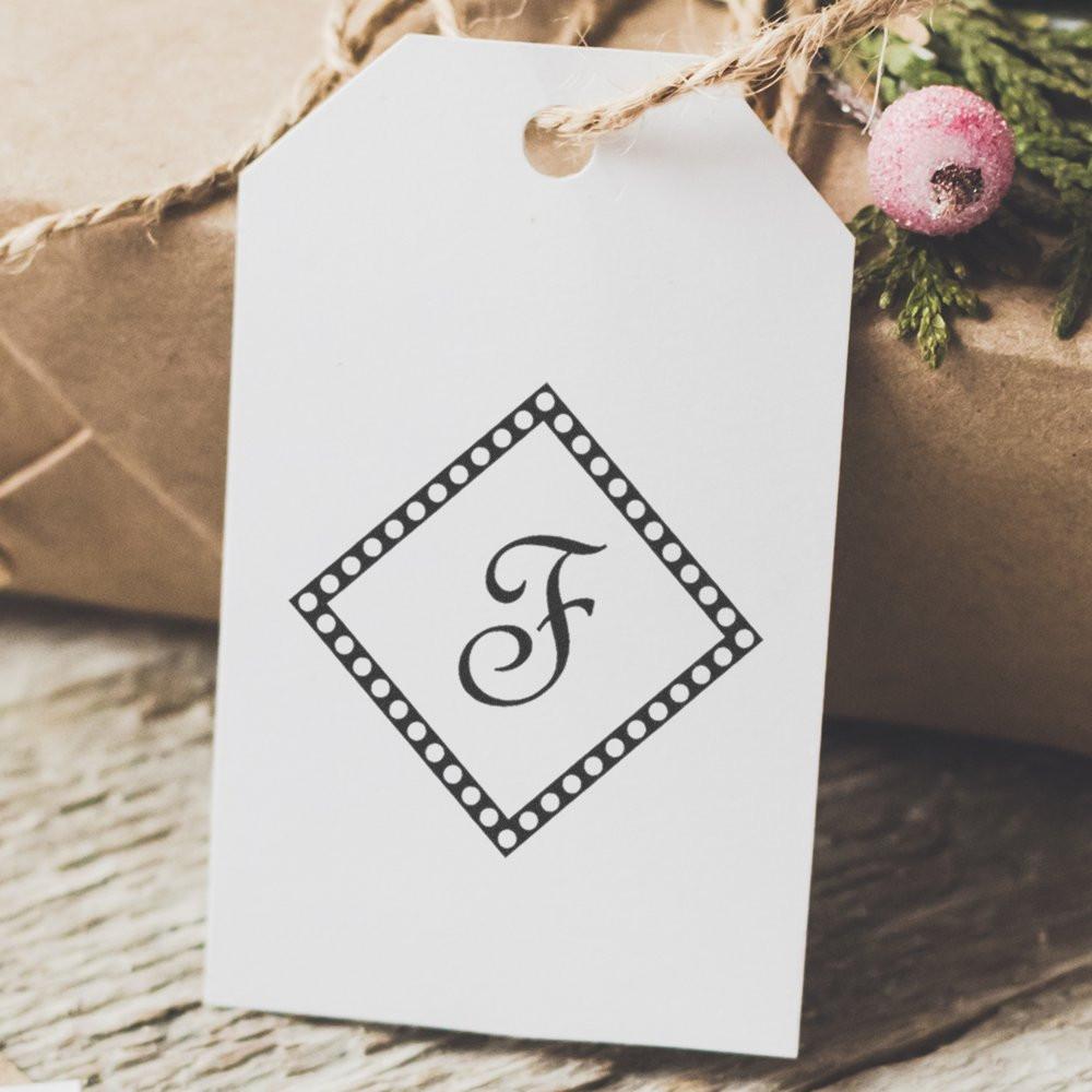 Custom monogram rubber stamp design on a white gift tag for wedding favors, gift packaging, and personalized branding.