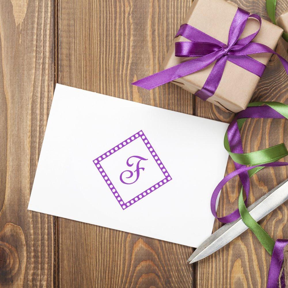 Personalized monogram F rubber stamp design on white card, styled for gift wrapping on rustic wood table.