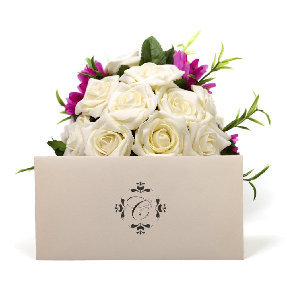 Custom floral monogram rubber stamp on a wedding gift box with white roses and pink blooms for personalized packaging.