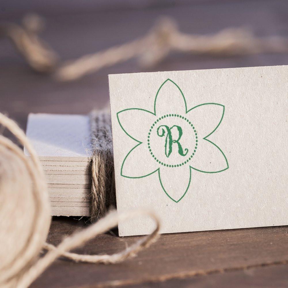 Floral monogram rubber stamp with letter R on cardstock, styled for custom wedding or branding stationery.