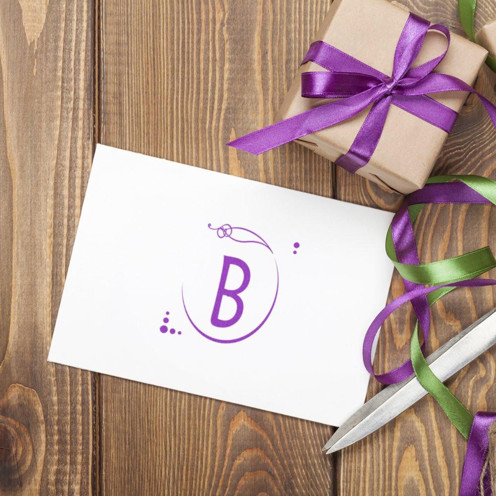 Personalized monogram B rubber stamp on a white card with purple ribbon and gift wrap for elegant packaging.