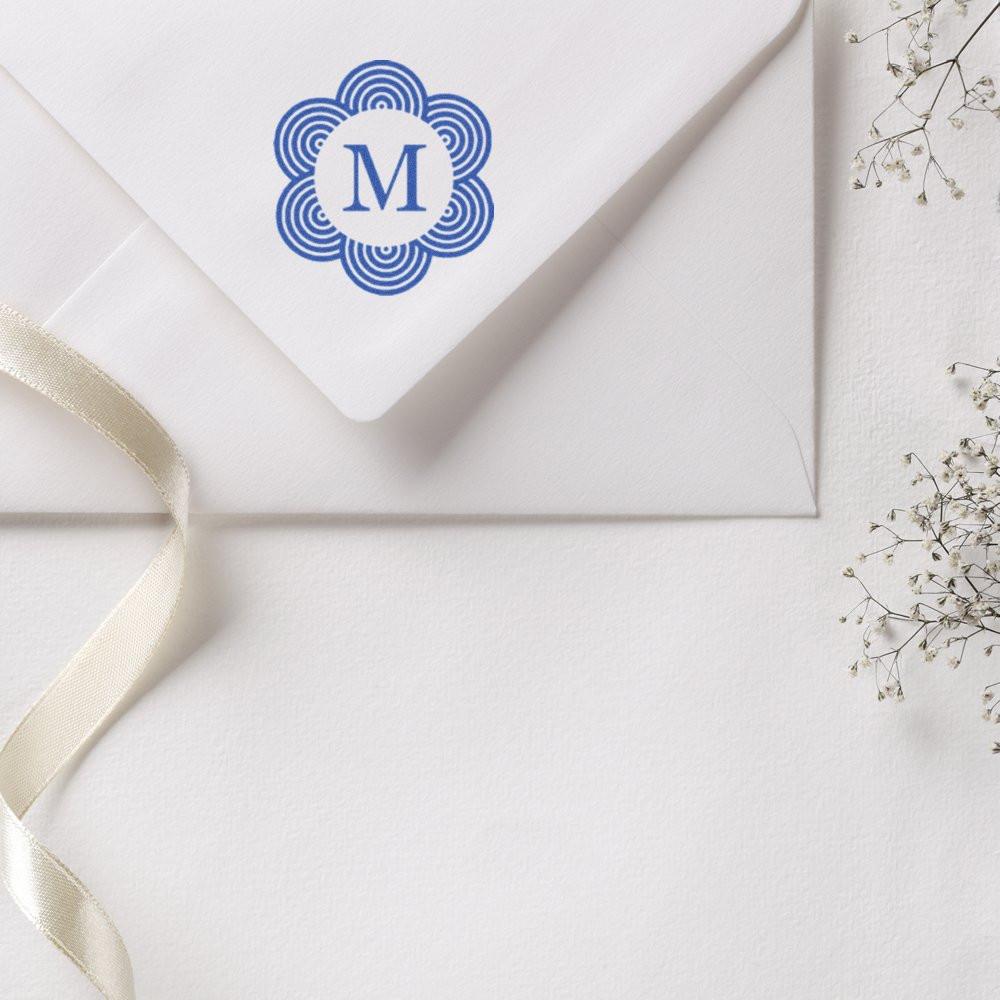 Personalized monogram rubber stamp with blue floral M design on a white envelope for elegant wedding stationery.