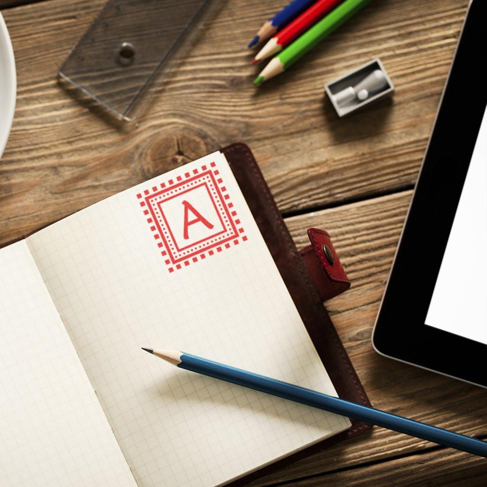 Custom rubber stamp with red letter A on notebook, ideal for personalized office branding, stationery, and classroom use.