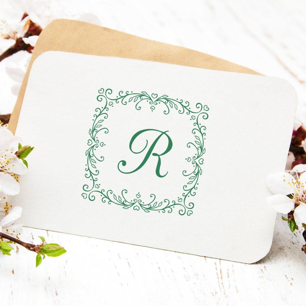 Custom monogram rubber stamp with elegant floral border and letter R for wedding stationery and branding.