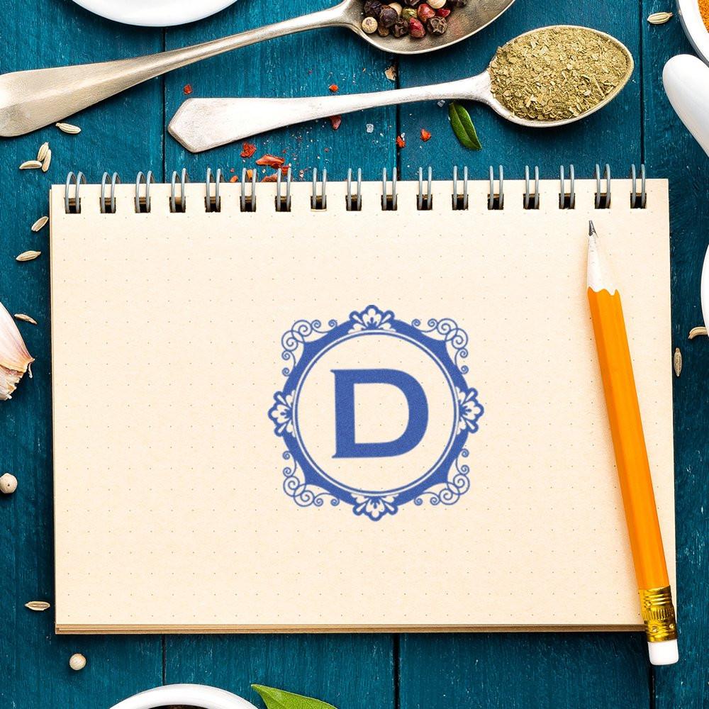 Ornate letter D rubber stamp on notebook page for custom monogram branding and personalized stationery.