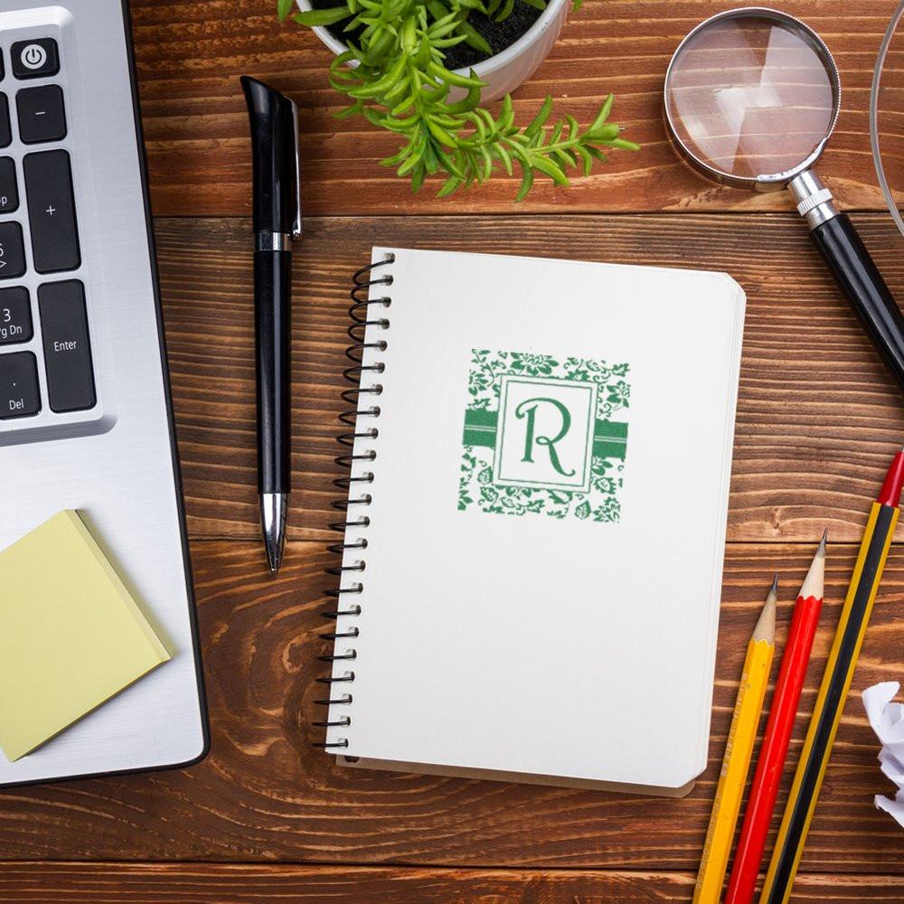 Custom monogram rubber stamp impression on notebook, shown in a creative office desk workspace.
