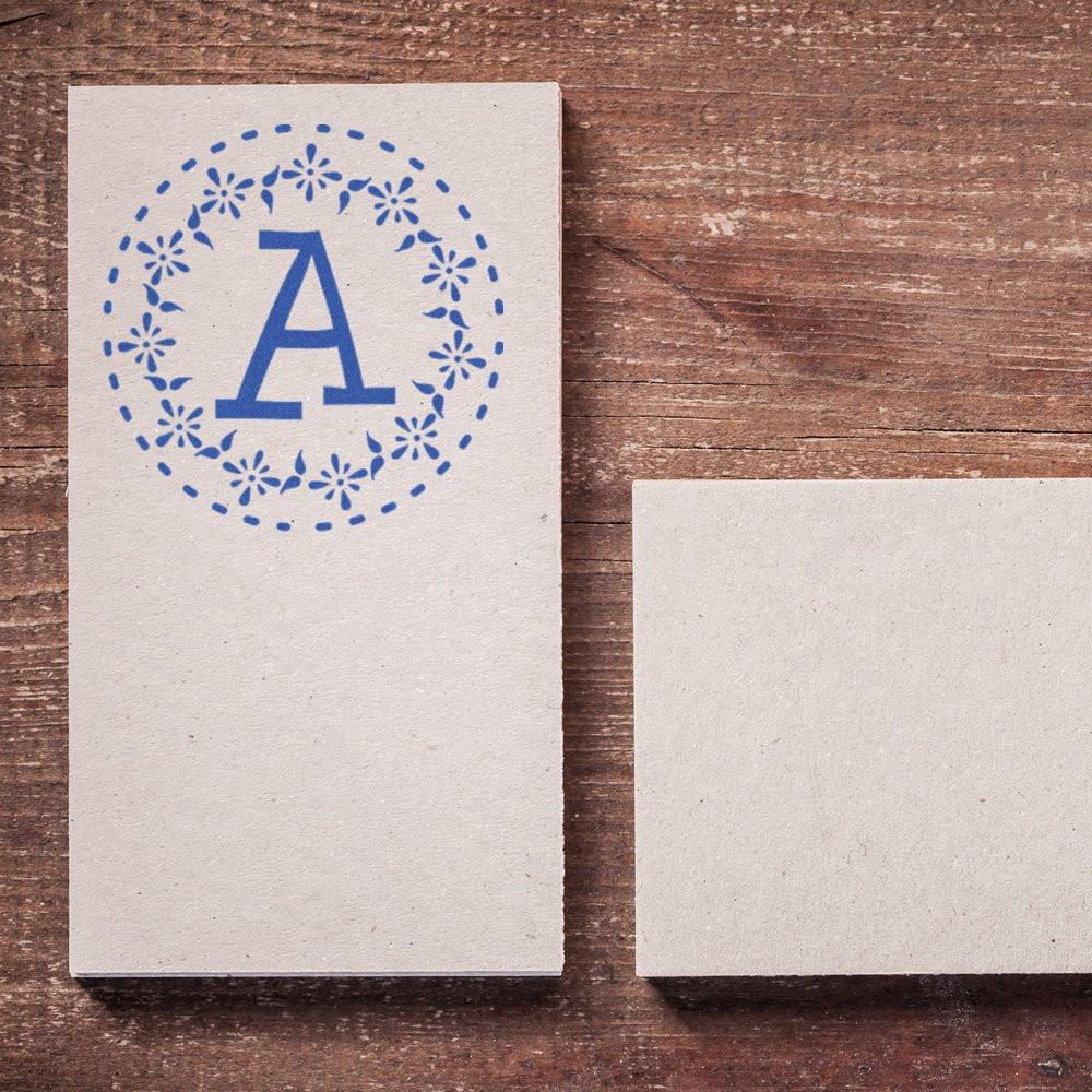 Custom monogram rubber stamp impression with floral letter A on blank card for personalized stationery and craft projects.