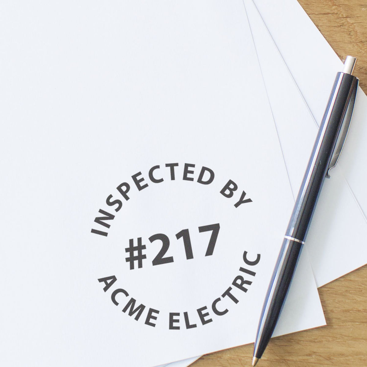 Inspecting ACME Electric paperwork with INSPECTED BY #217 stamp and pen on desk for quality control documentation.