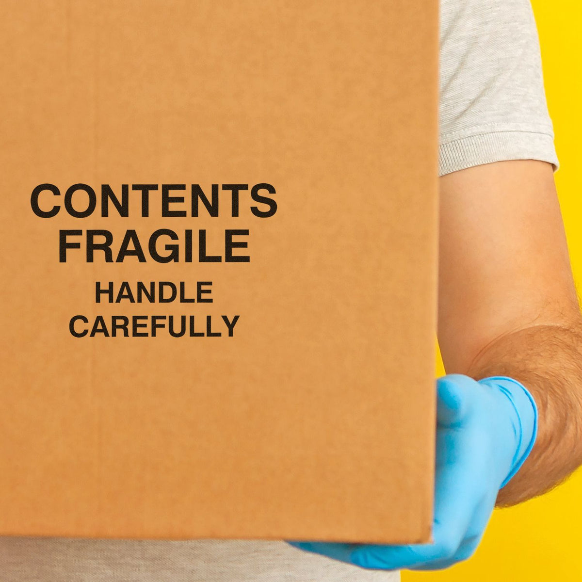 Fragile shipping box with contents handle carefully label, held by a person wearing blue gloves.