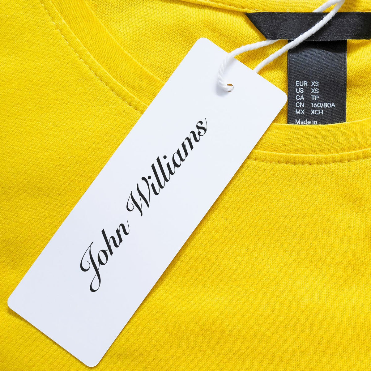 Yellow Williams T-shirt with branded clothing tag and size label close-up.