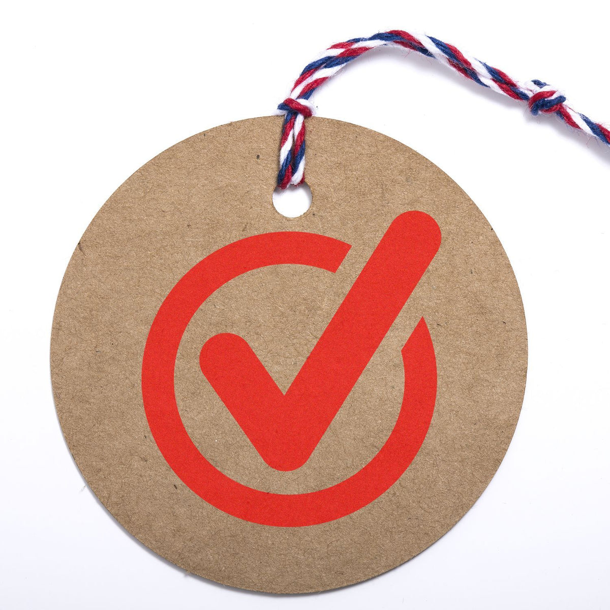 Kraft gift tag with red check mark and striped twine, symbolizing approval, quality, and order confirmation.