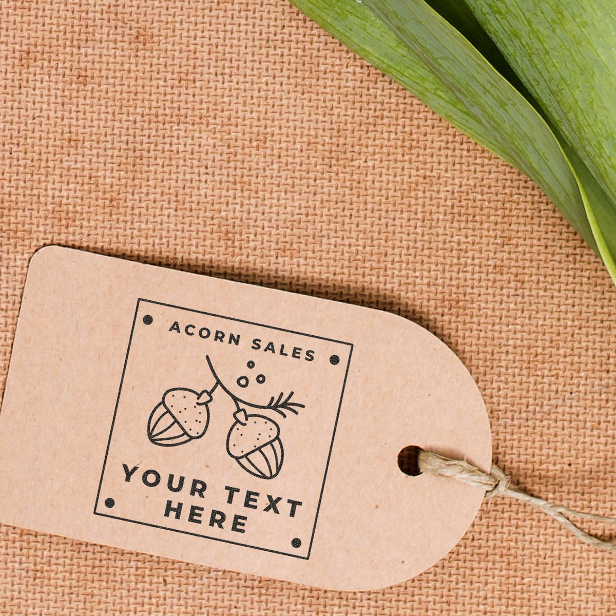 Acorn Sales label on kraft cardboard packaging with acorn illustration and leaf on burlap background for rustic brand branding.