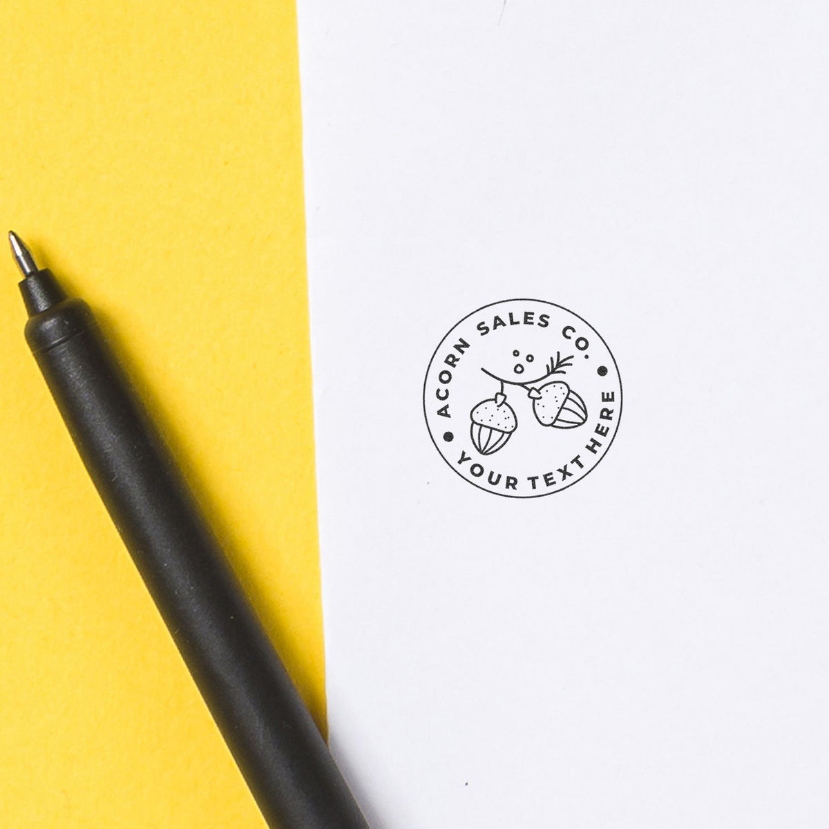Yellow notepad and black pen with Acorn Sales Co logo stamp for sales branding and contact info.