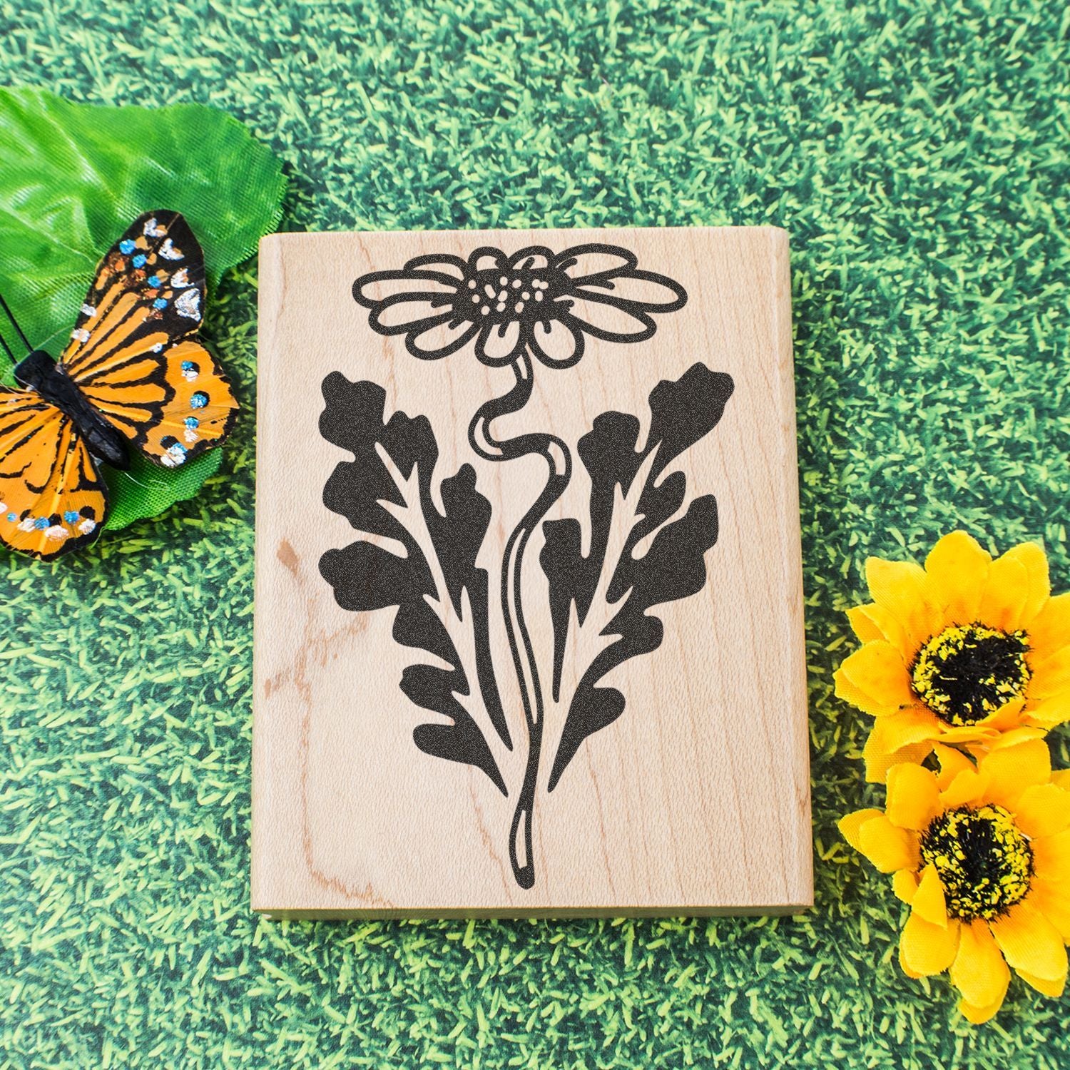 Rustic wooden floral sign with butterfly and yellow flowers on green grass background.