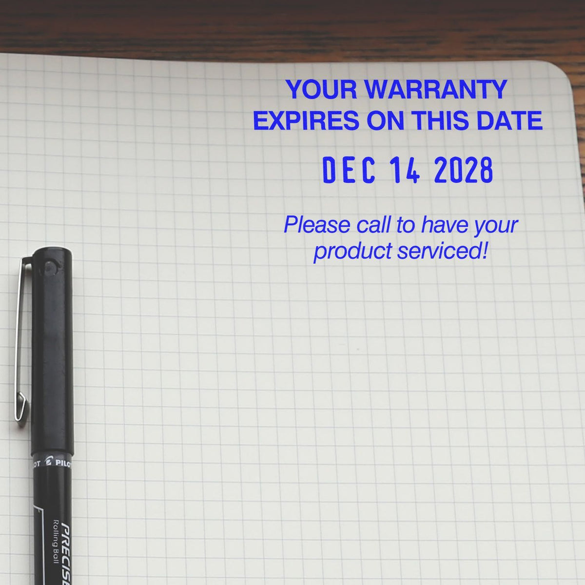 Notebook page with blue text showing warranty expiration date, Dec 14 2028, and a pen beside the message.