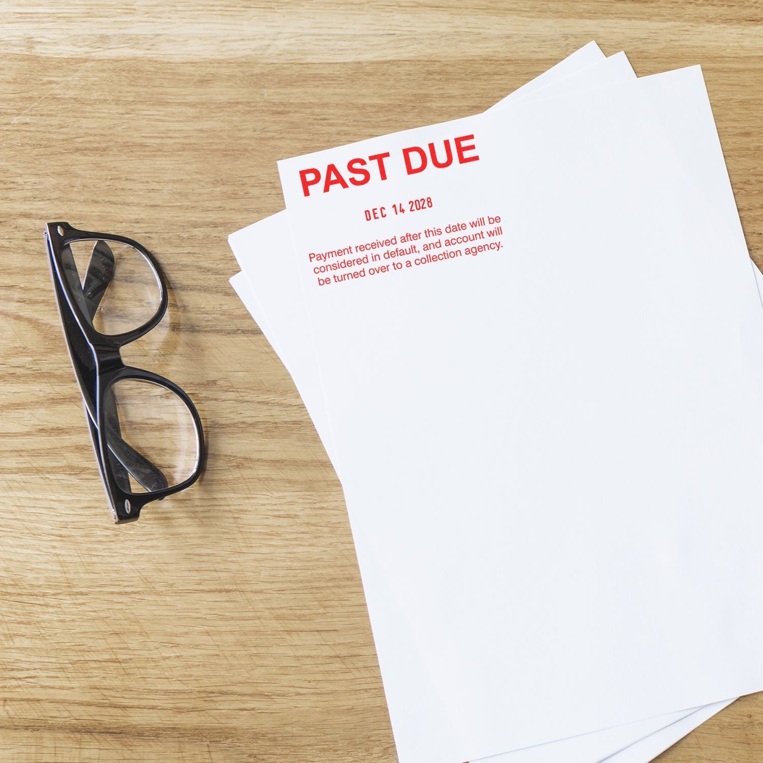 Past due bill notice with eyeglasses on a wooden desk, representing unpaid invoice and late payment reminder.