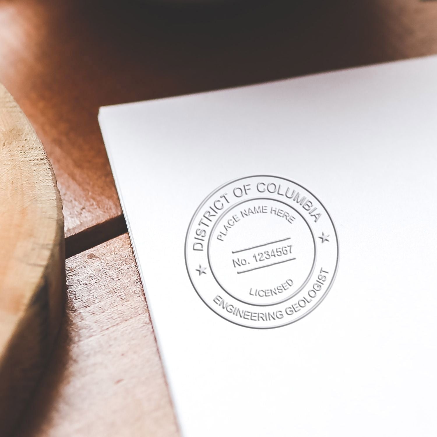 Close-up of a District of Columbia licensed engineering geologist embossed seal on a white document on a wooden desk.