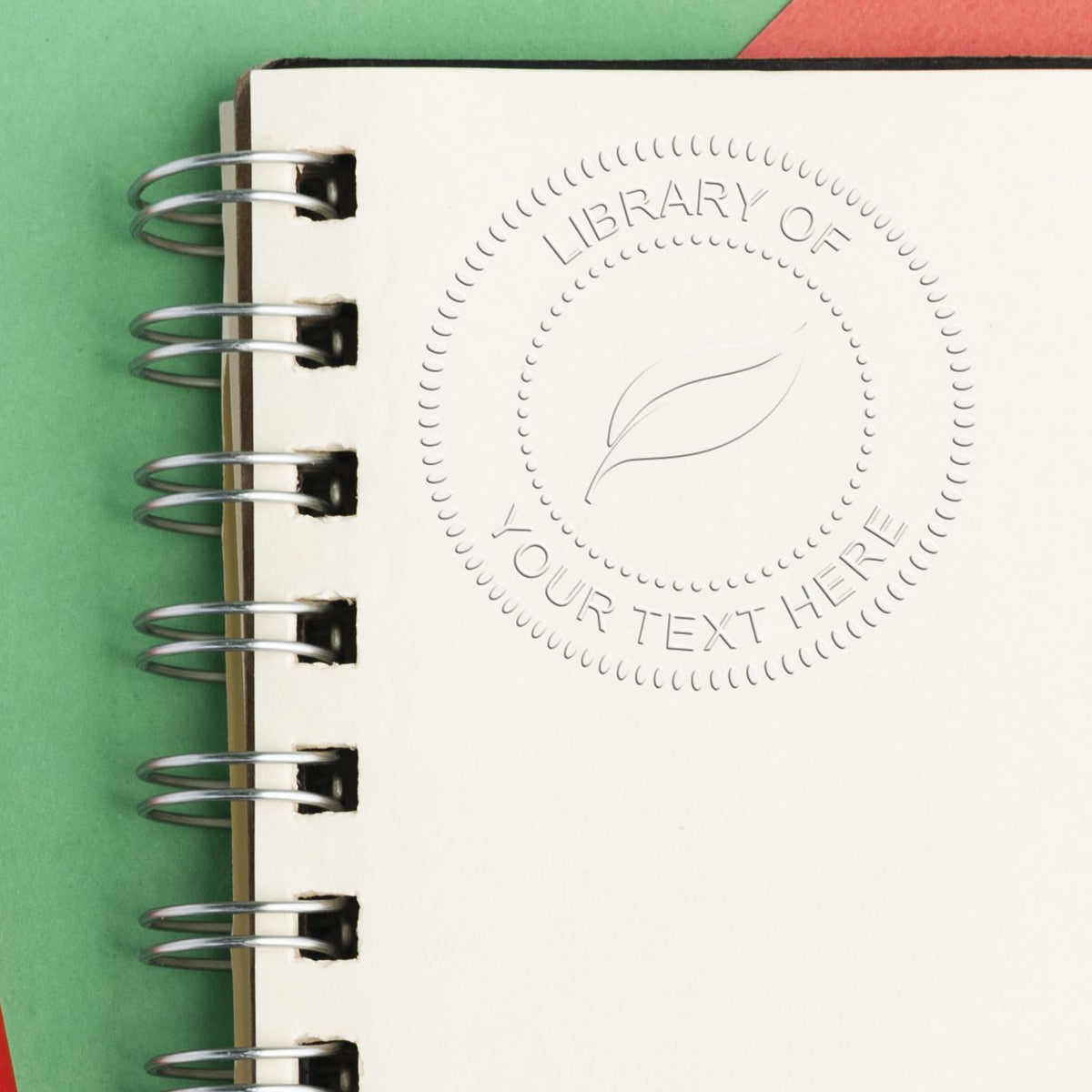 Spiral-bound notebook mockup with embossed logo and text placeholder on a green background, ideal for branding and stationery design.