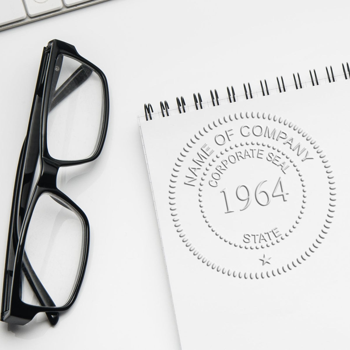 Black eyeglasses beside a notepad with corporate seal and 1964 embossing on a clean white desk, office flat lay.
