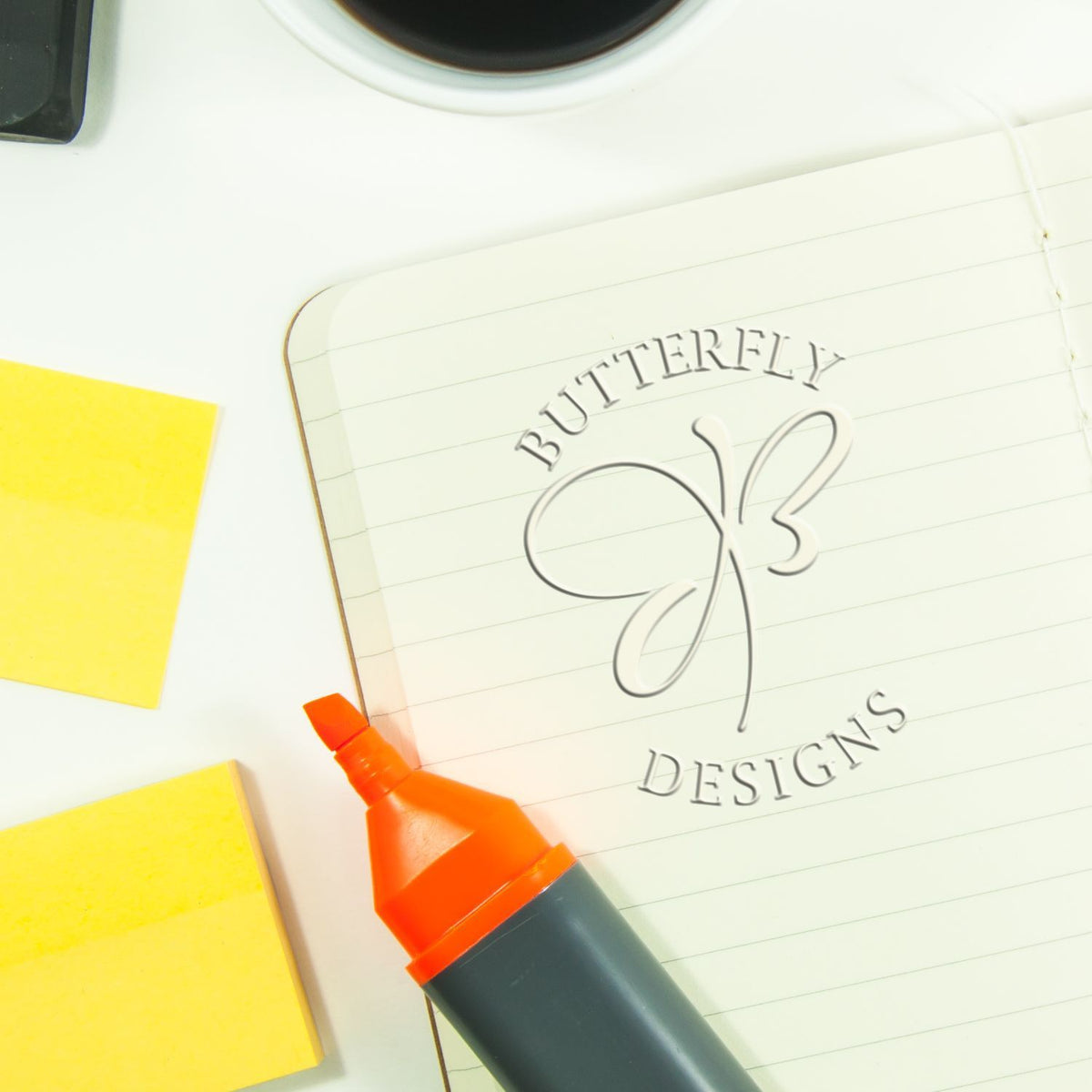 Butterfly Designs logo on a notebook with marker and sticky notes on a clean office desk.
