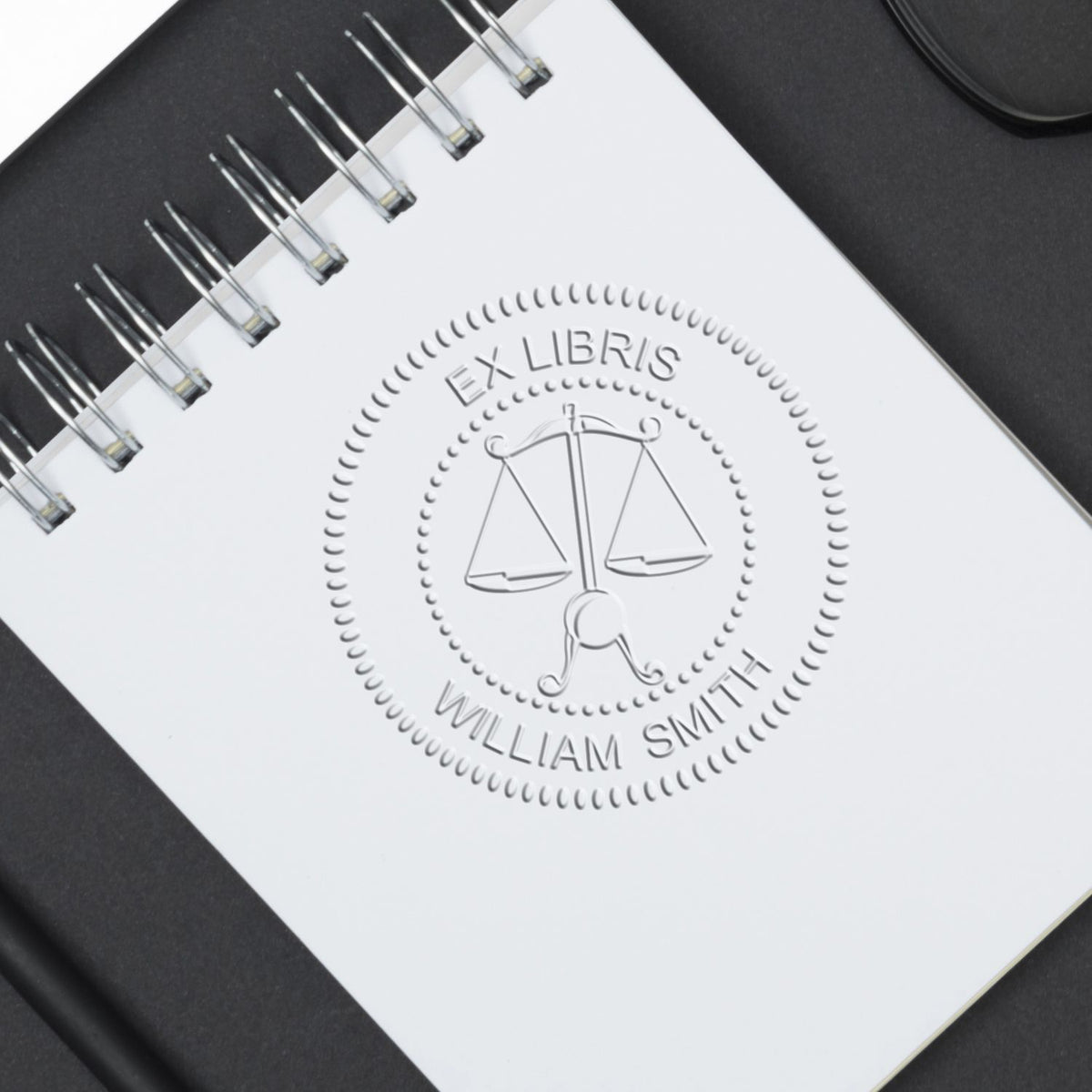 Spiral-bound notebook with embossed Ex Libris William Smith scales of justice logo on a white cover