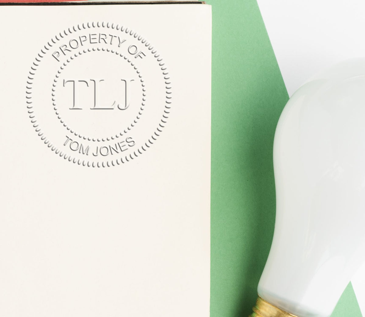 Embossed Property of TLJ Tom Jones notebook cover on a green background with a white bottle.