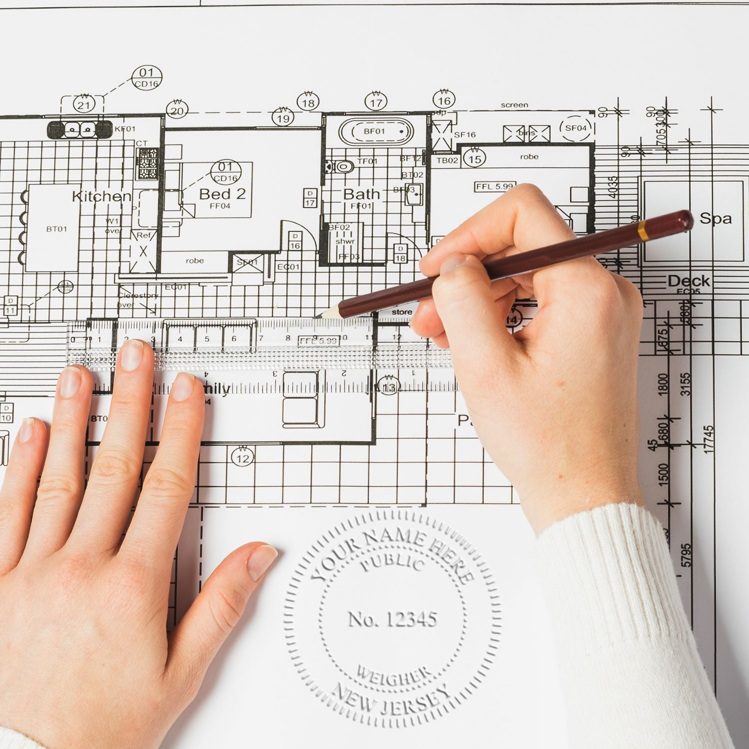 Hands drawing on an architectural floor plan with a pencil and ruler, showing home design and drafting measurements.