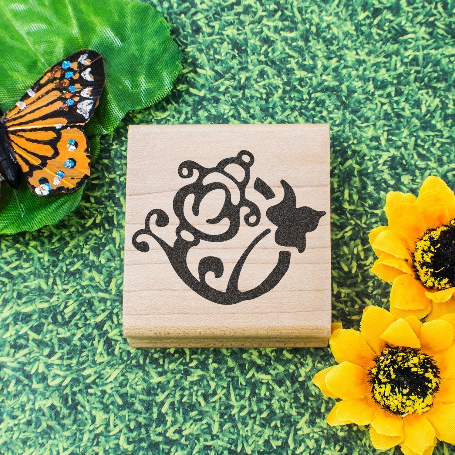 Butterfly and sunflower decorative stamp on a wooden block with green grass background