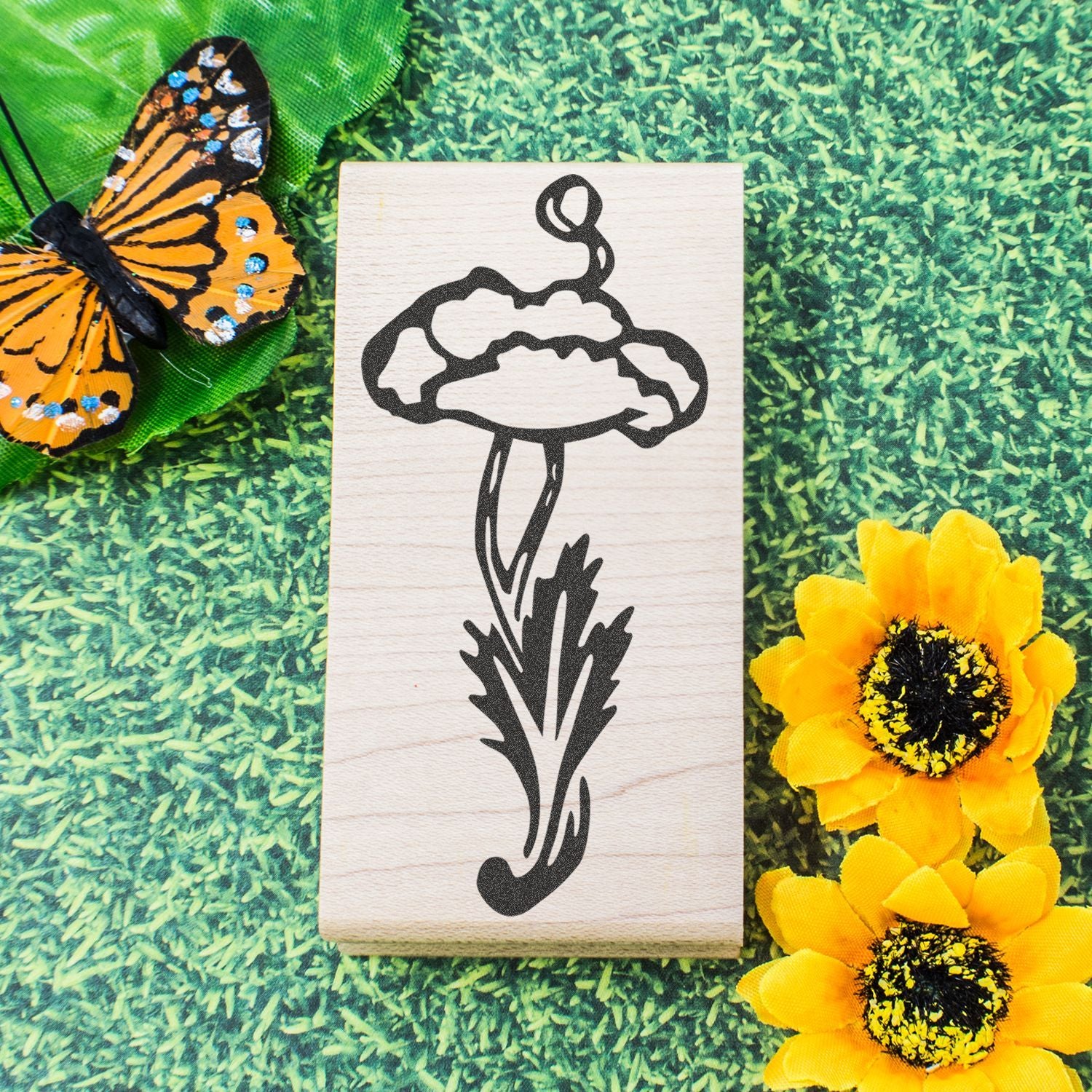 Wooden mushroom stamp design with butterfly and yellow flowers on a green grass background