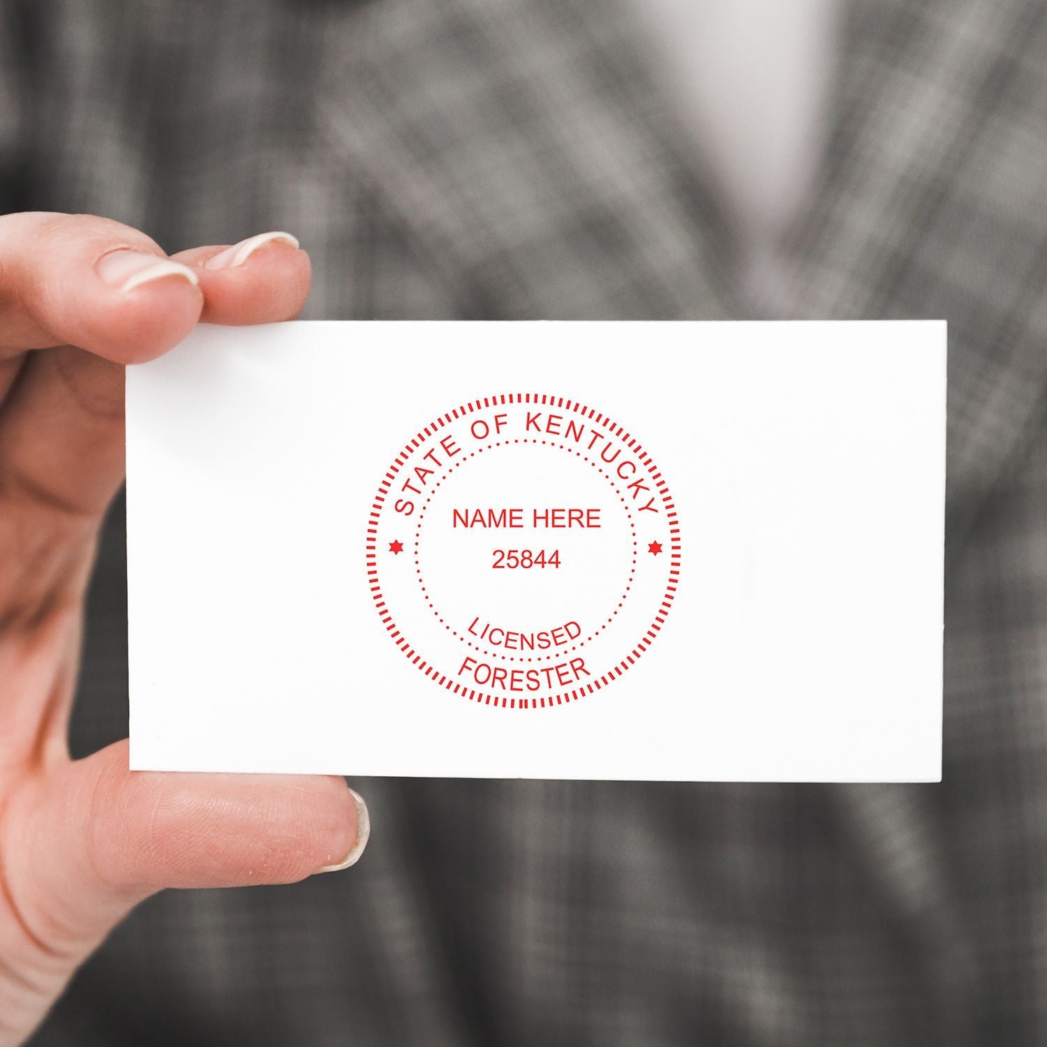 Hand holding a Kentucky licensed forester business card with red official seal logo.