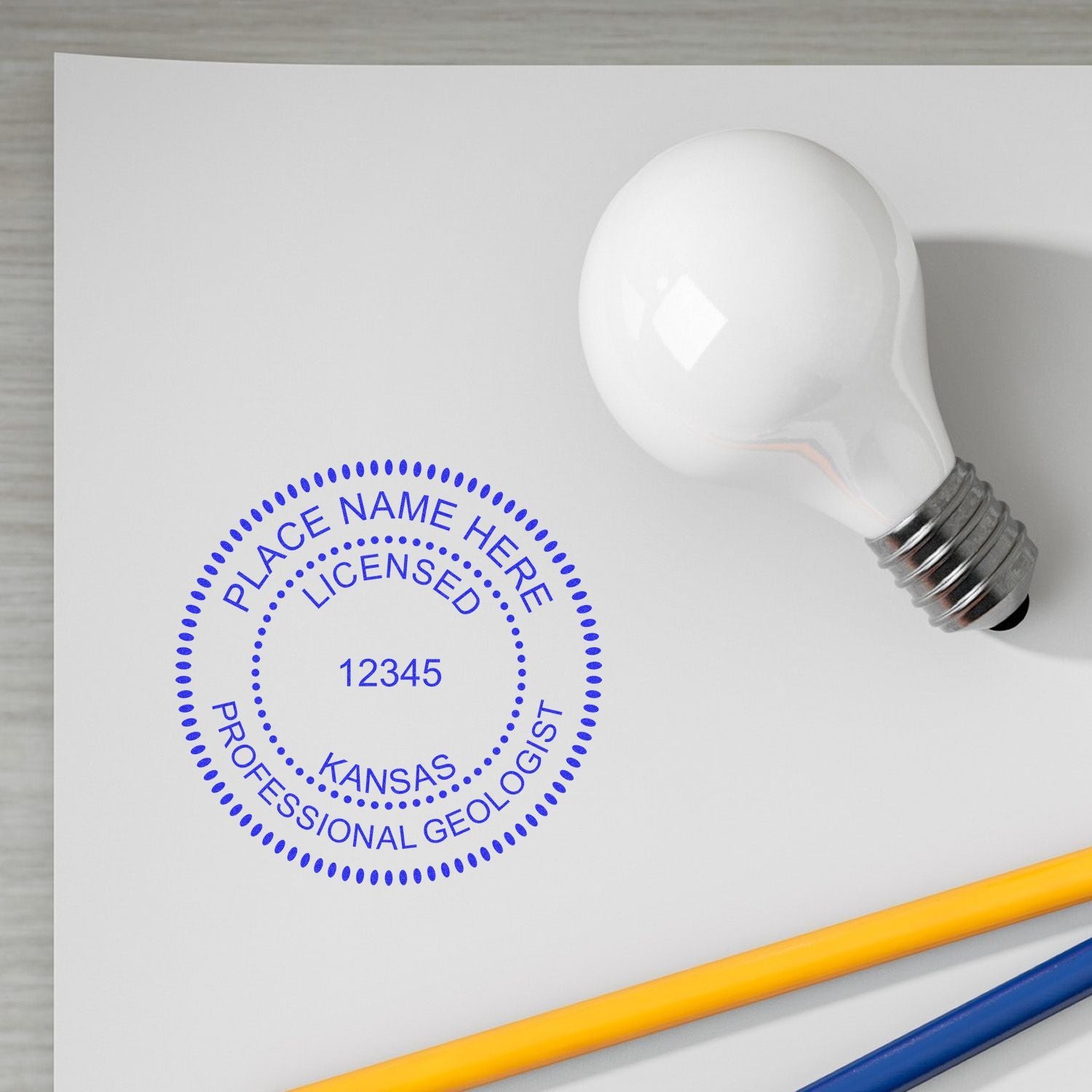 Kansas professional geologist license stamp mockup on white paper with light bulb and pencils.