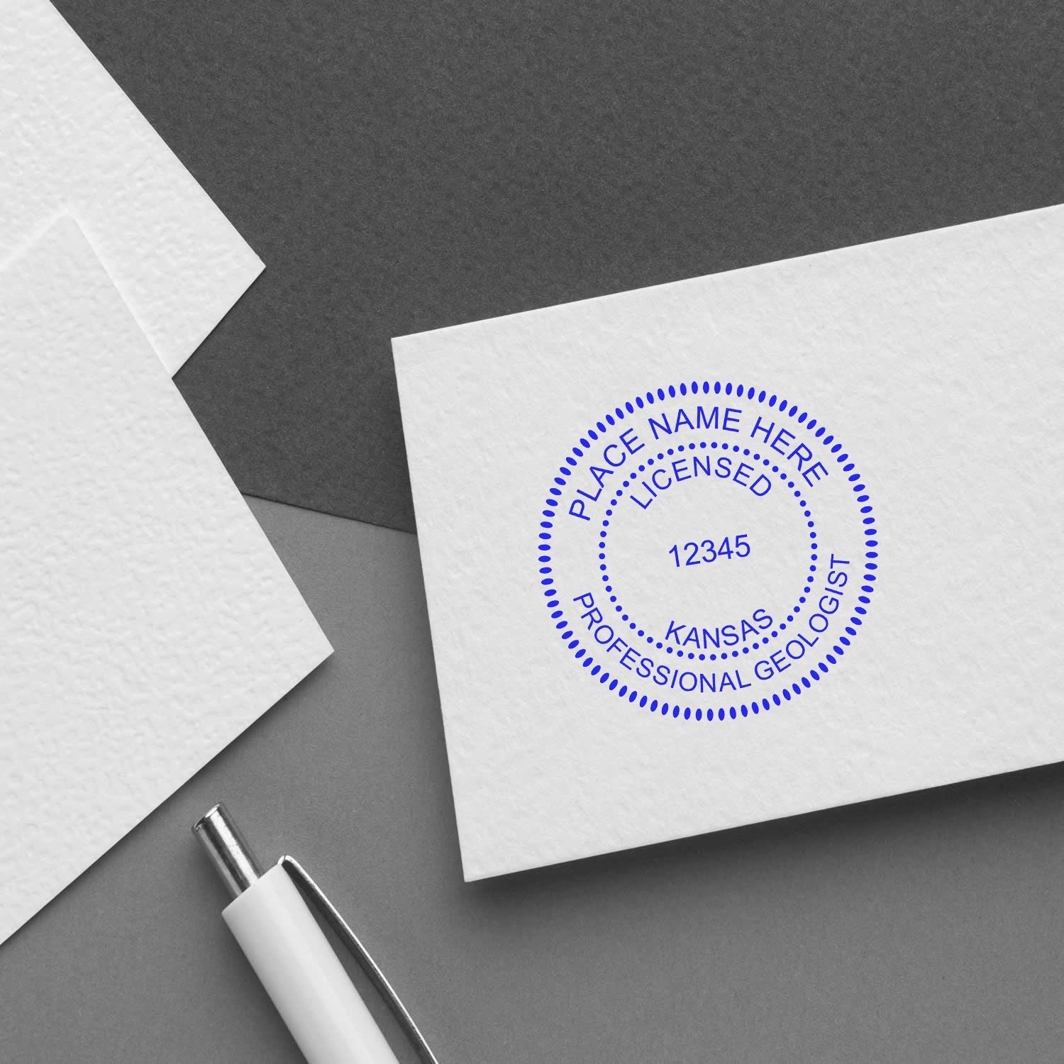 Close-up of white envelope stamped with Kansas licensed professional geologist seal and pen on desk.