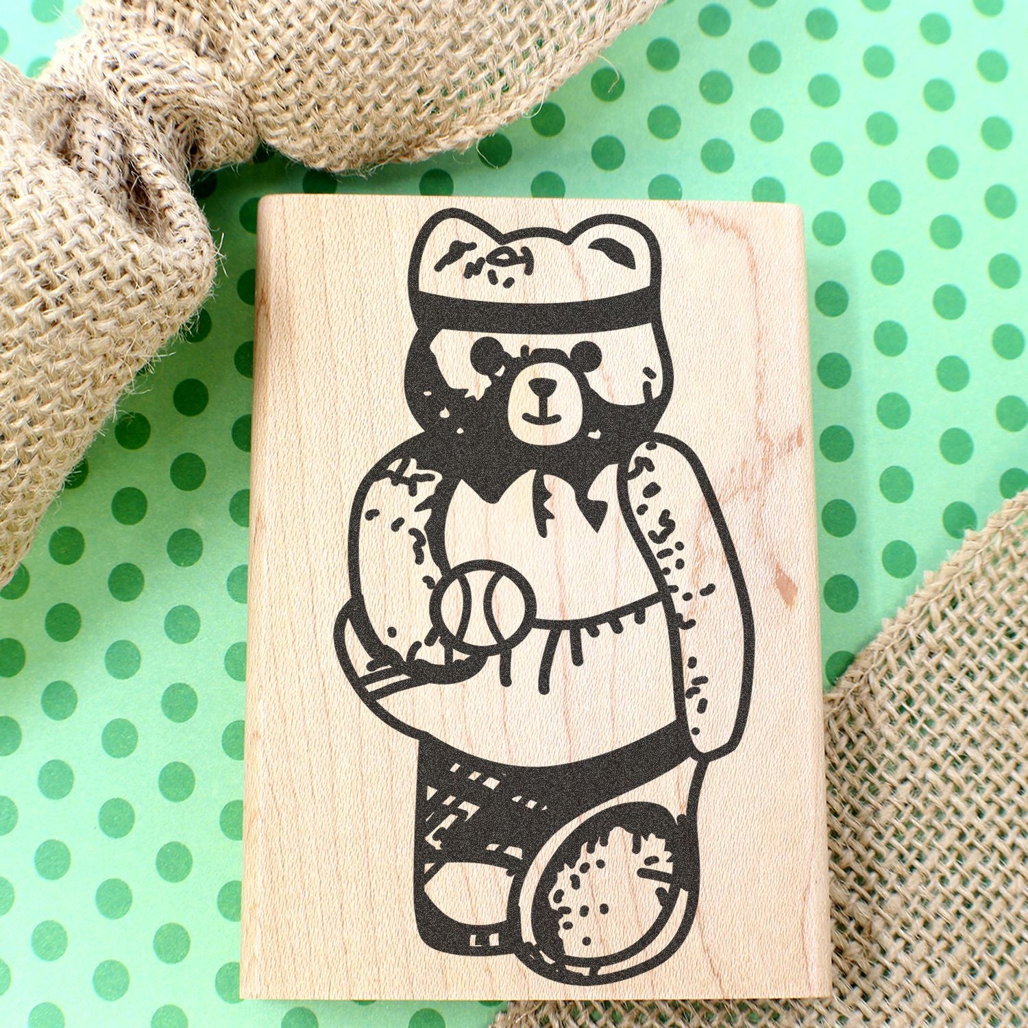 Wooden bear stamp illustration on a green polka dot background with burlap fabric accents.