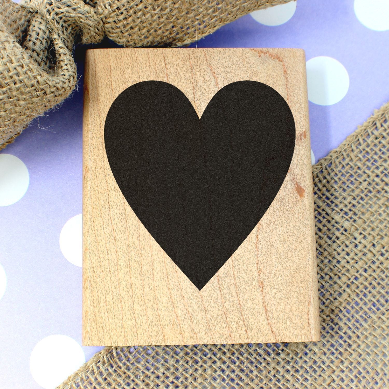 Wooden heart sign with black heart on a polka dot background and rustic burlap decor, perfect for love and Valentines Day themes