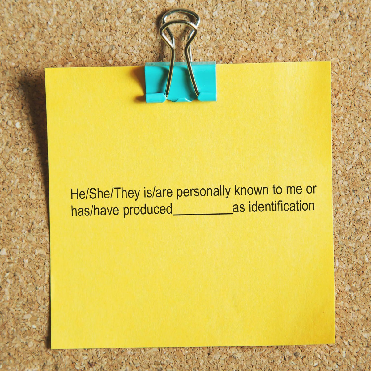 Yellow note clipped to a corkboard with a blue binder clip, showing identification verification text.