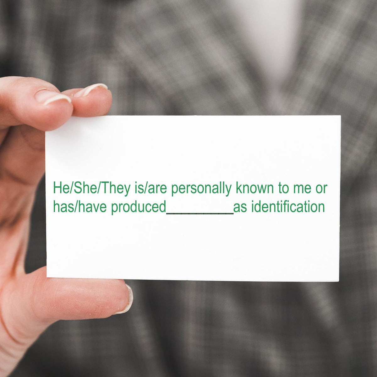 Hand holding a white identification card with green text for identity verification and personal recognition.