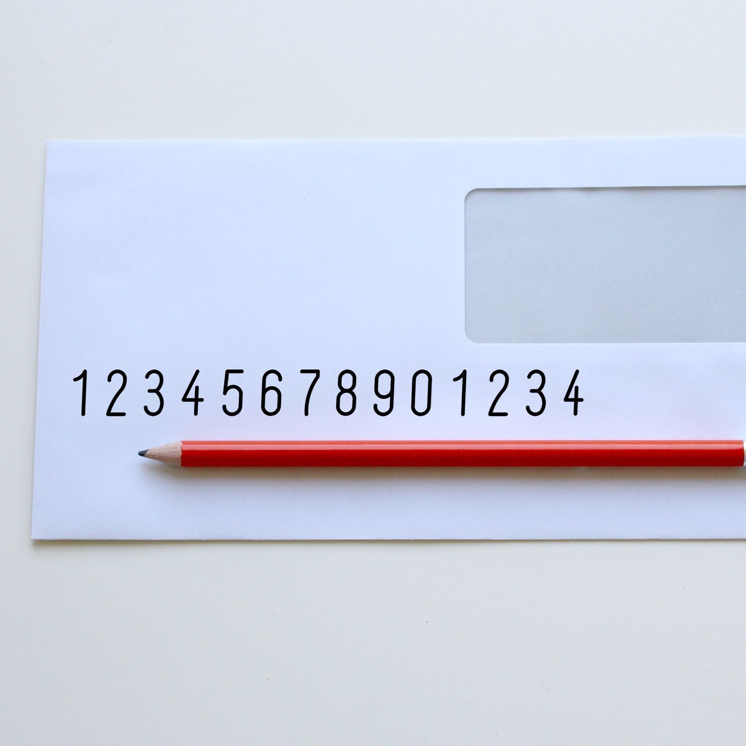 Red pencil aligned with printed number sequence 12345678901234 on an educational math practice sheet for numeracy