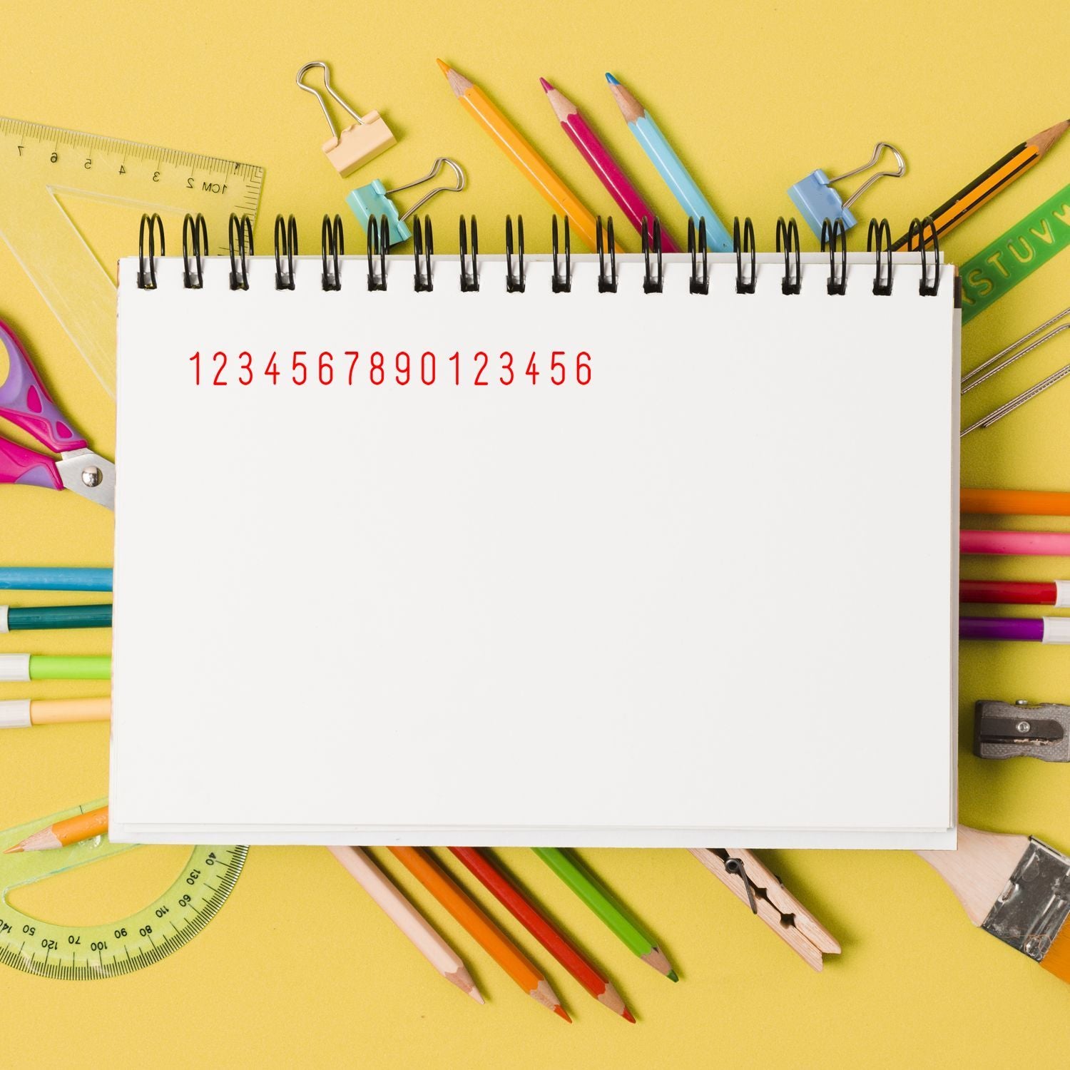 Blank lined notebook on colorful school supplies background with pencils, ruler, and paper clipseducation and back-to-school concept.