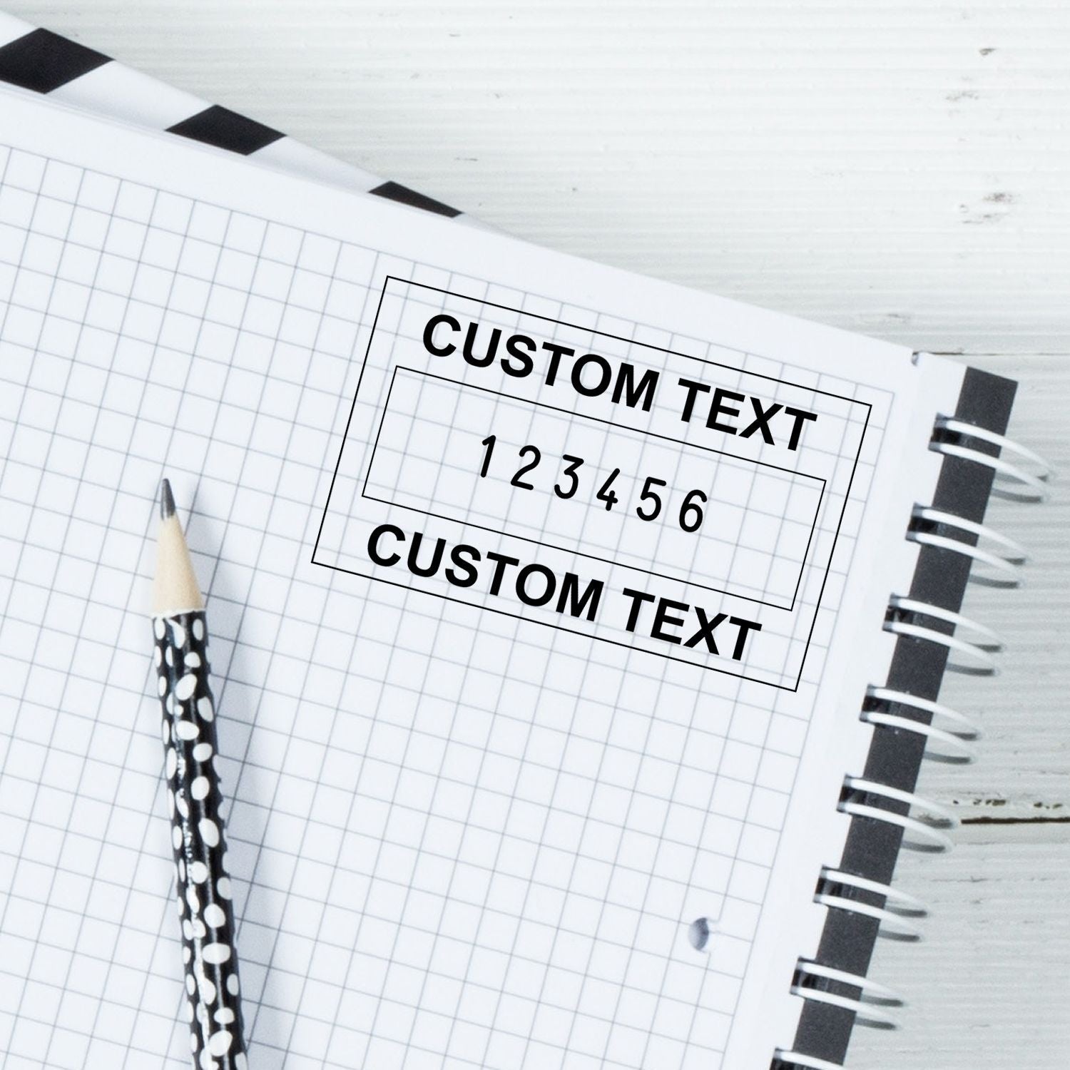 Notebook grid with custom text template, showing CUSTOM TEXT and numbers 16, pencil and binder rings for marketing copywriting planning.