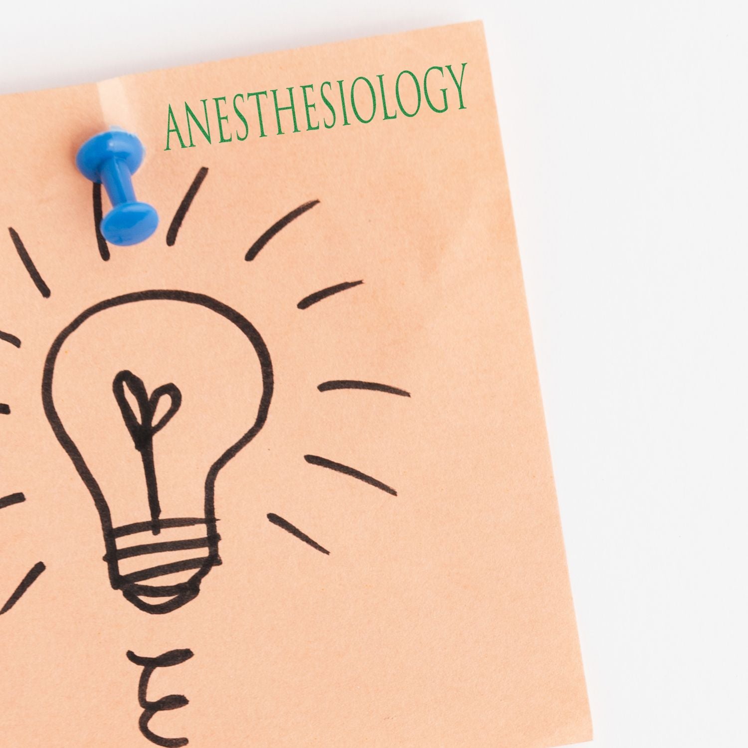 Anesthesiology concept note with light bulb idea sketch pinned by a blue pushpin on a paper background.