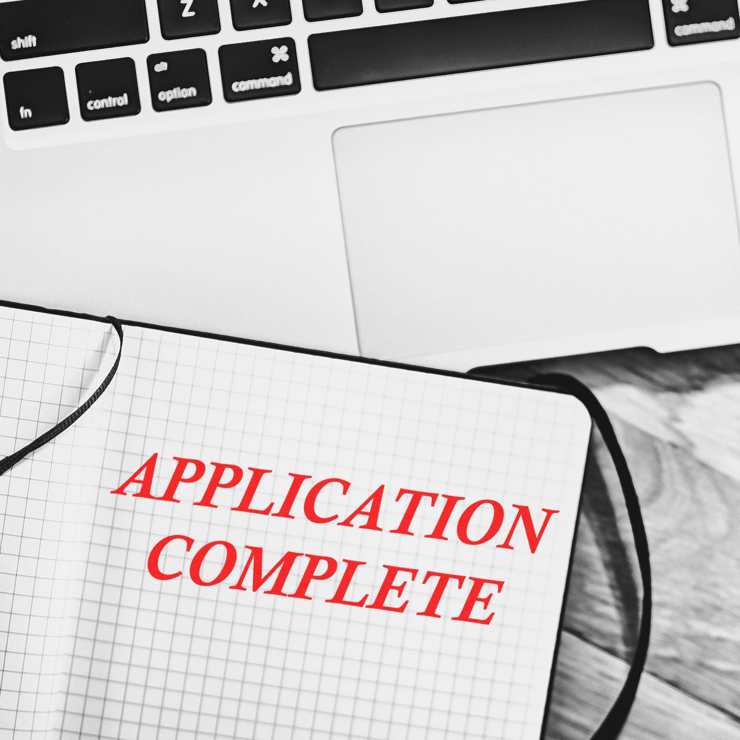 Application complete text in a notebook beside a laptop keyboard, representing online job application submission.