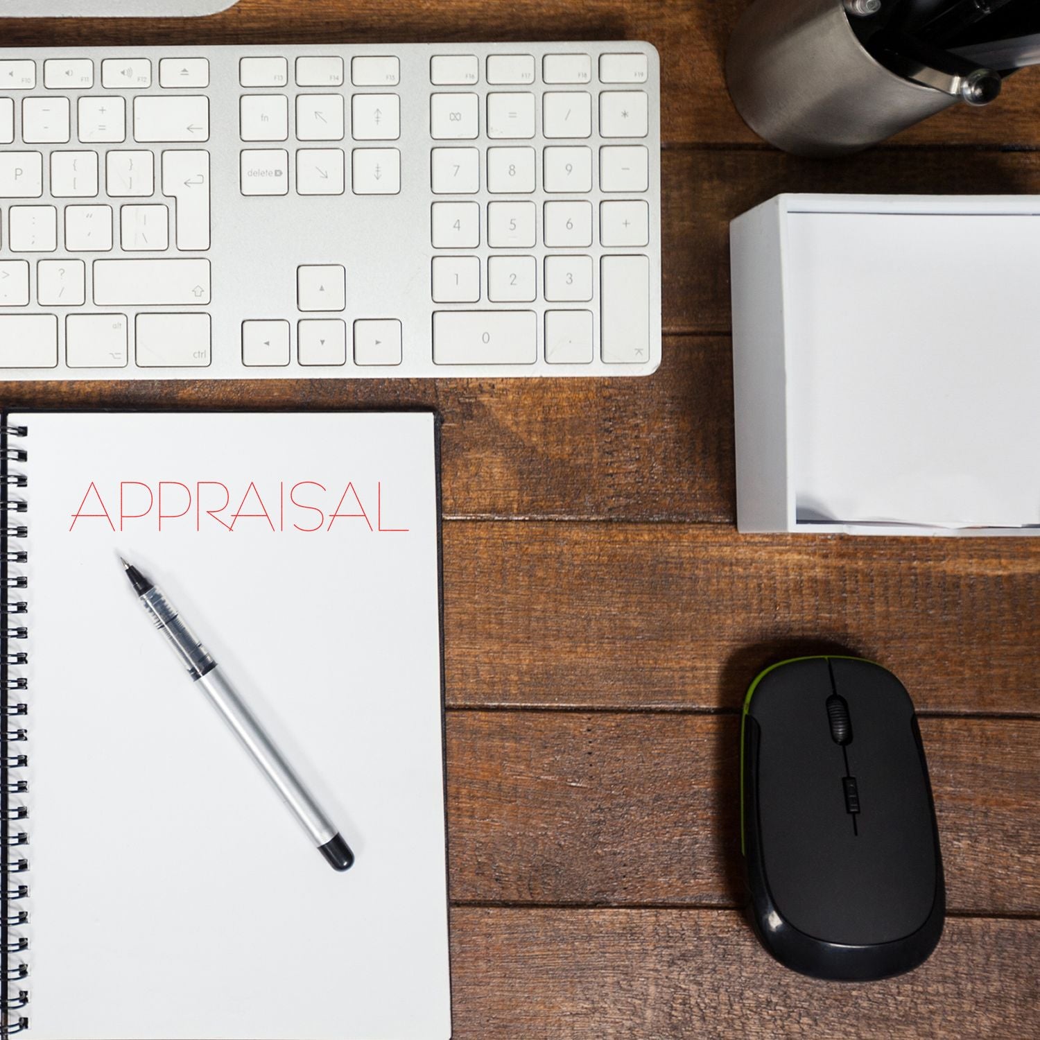 Appraisal notebook on wooden desk with keyboard, mouse, pen, and office supplies for business valuation work