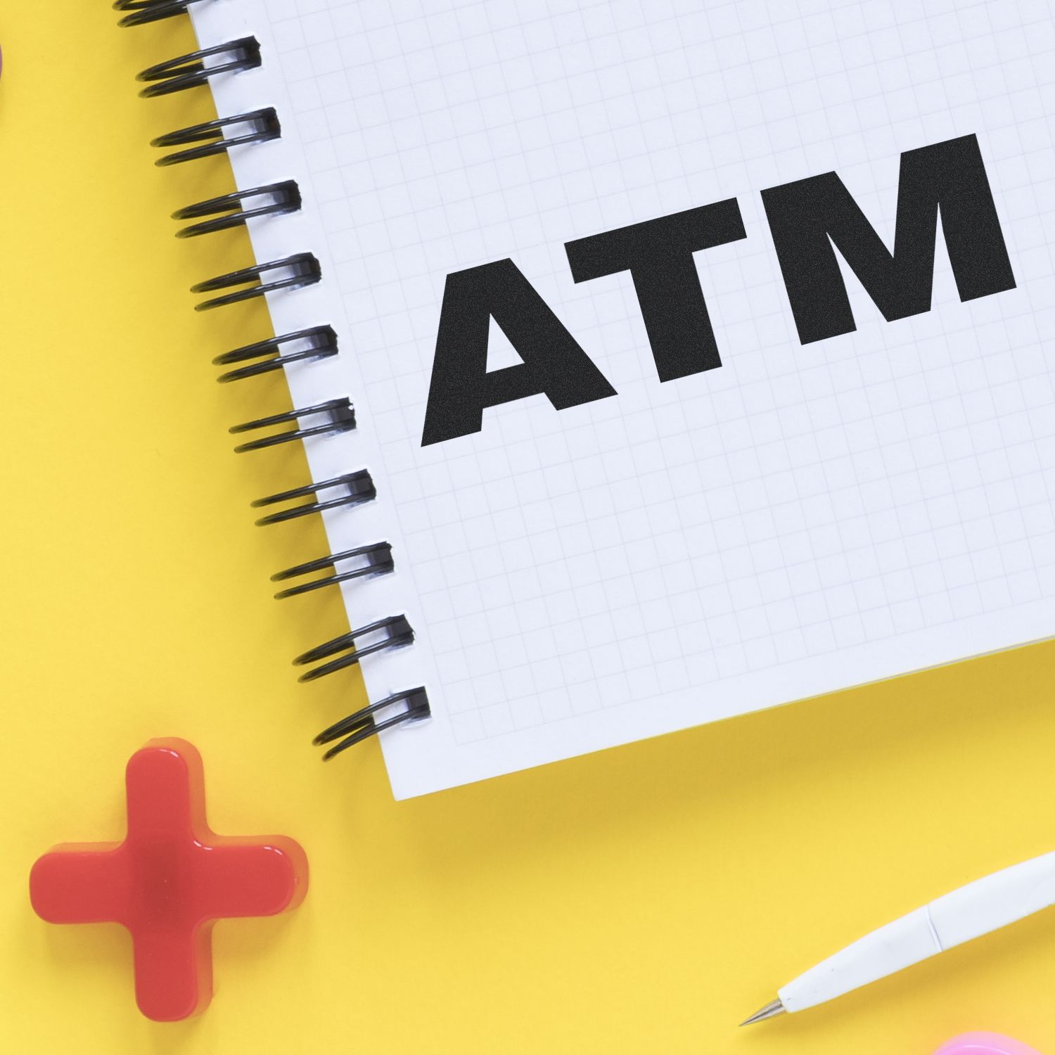 First aid concept: red medical cross beside notebook page with ALT lettering on bright yellow background.