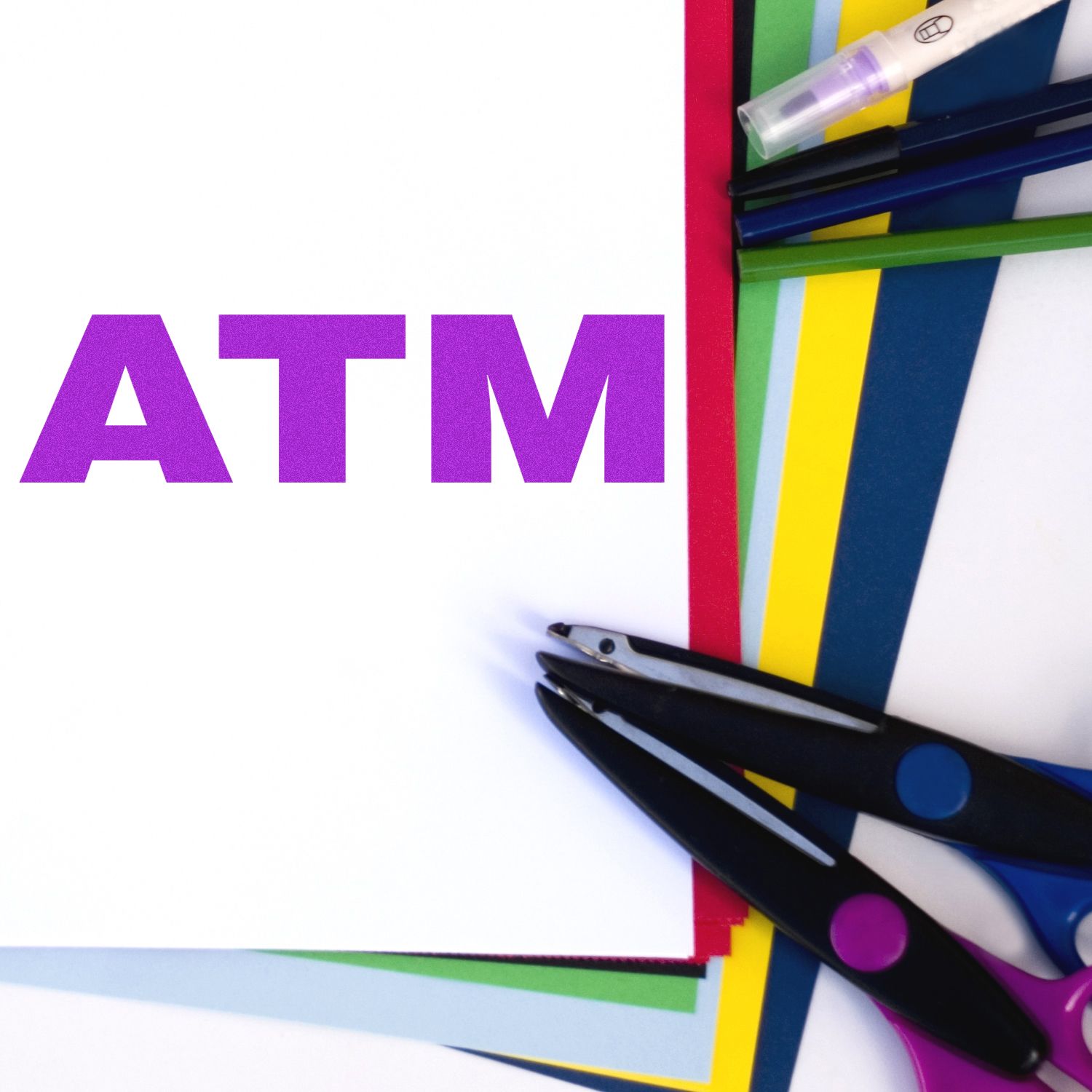 Large purple ATM letters on colorful craft paper with scissors and art supplies, showing DIY educational crafting theme.