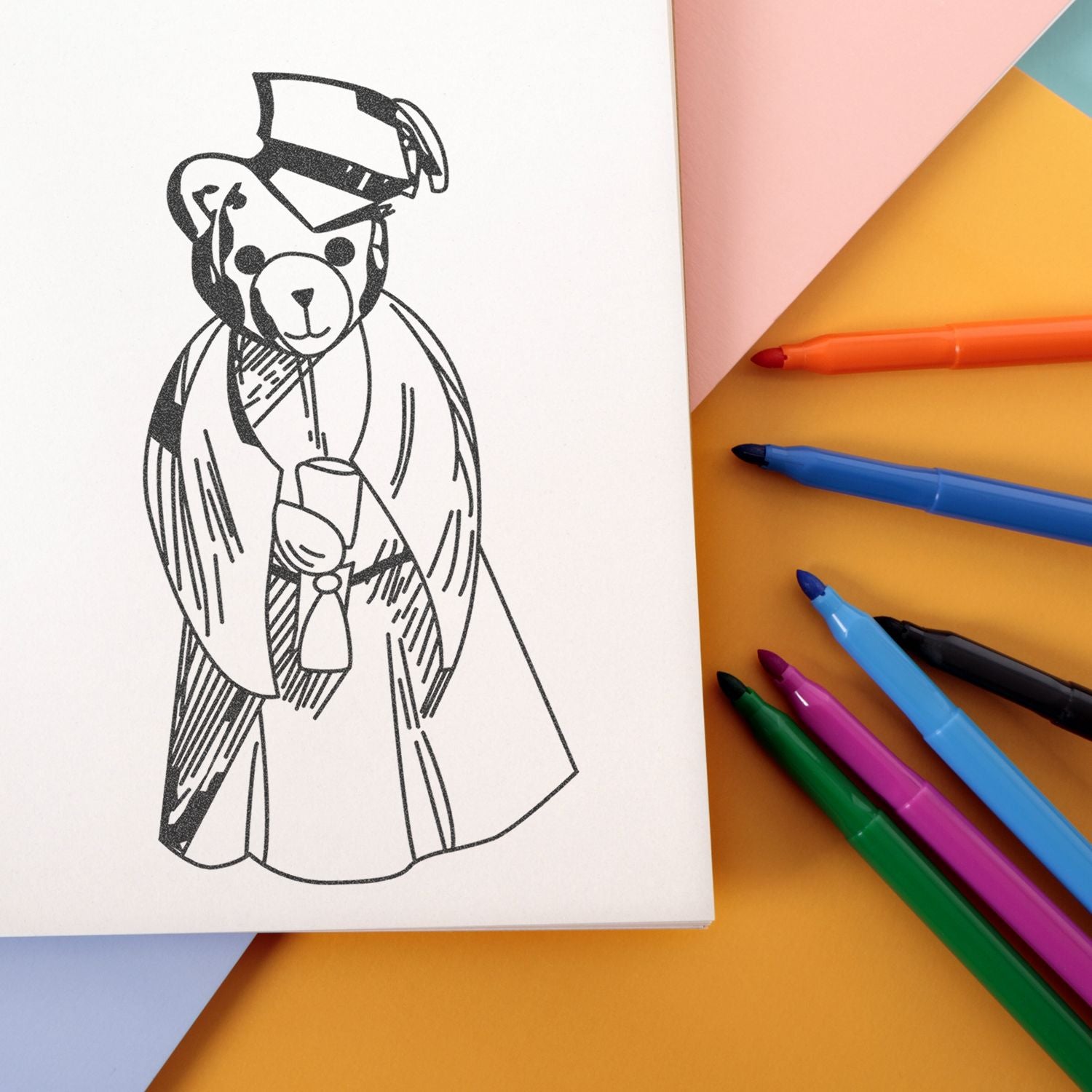 Teddy bear graduation coloring page with colorful markers on pastel paper background