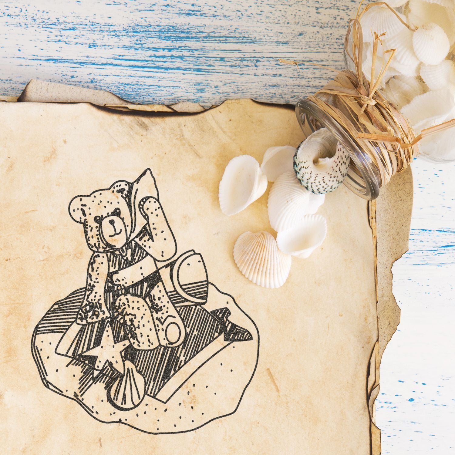 Vintage beach-themed flat lay with seashells, rustic jar decor, and a teddy bear illustration on aged paper against a weathered blue wooden background.