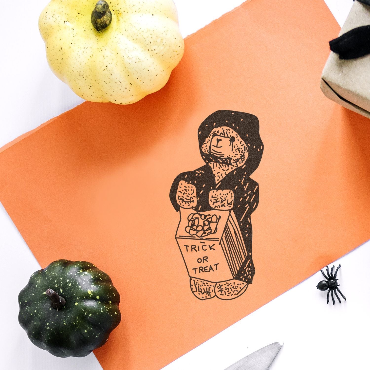 Halloween trick or treat card with illustrated child, pumpkins, and spider on orange paper background