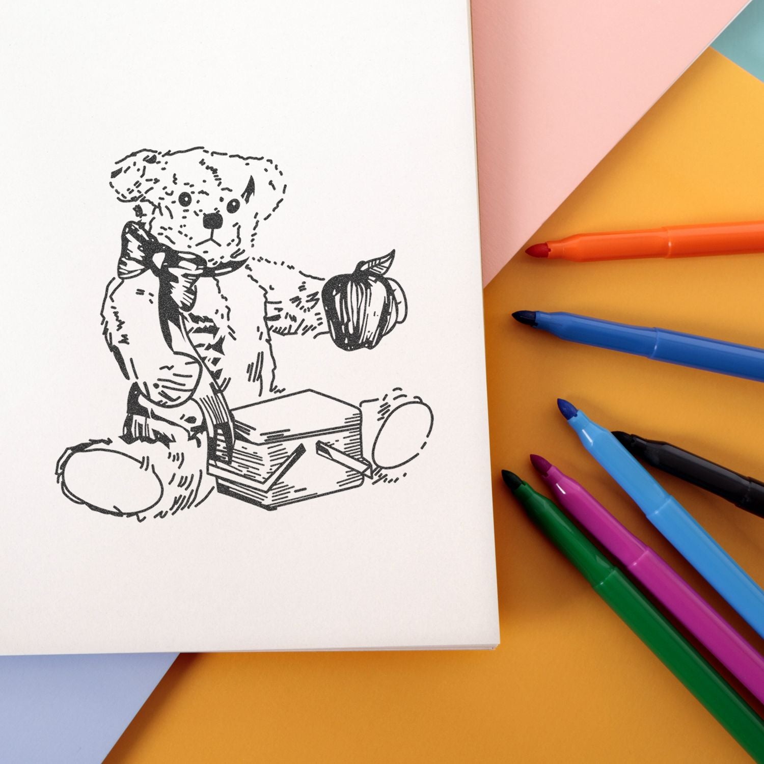 Teddy bear sketch on notebook with colorful markers and pastel paper flat lay.